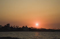 Sunset over silhouetted Kos town with low sun reflected in rippled water.Greek IslandsAegeanMediterraneanKossummerseasonholidaydestinationtraveDestination Destinations Ellada European Greek S...