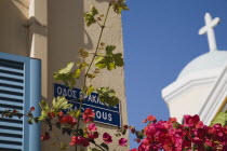 Iracleous Place street sign on corner of building opposite partly seen Agia Paraskevi Greek Orthodox church in Kos Town with dark pink bougainvillea in foreground.Greek Islands clear blue skysummer...