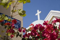 Iracleous Place street sign on corner of building opposite partly seen Agia Paraskevi Greek Orthodox church in Kos Town with dark pink bougainvillea in foreground.Greek Islands clear blue skysummer...