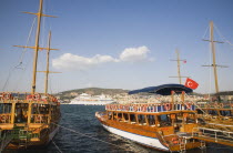Tourist cruise boats moored in harbour with cruise ship and coastline beyond.TurkishAegeancoastresortsummersunshineearly summer seasonMediterraneanholidayDestination Destinations Ellada Euro...