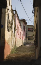 Flight of steps through narrow street lined by pale pinks and cream painted houses.TurkishAegeancoastresortsummersunshineearly summer seasonMediterraneanholidayDestination Destinations Ellad...