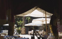 View towards outside cafe tables and display of carpets from beneath canopy of Turkish coffee stall.TurkishAegeancoastresortSummersunshineearly Summer seasonholidaydestinationdestinations El...