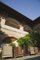 Display of traditional carpets outside building with colonnaded balcony and overhanging roof.TurkishAegeancoastresortSummersunshineearly Summer seasonholidaydestinationdestinations ElladaEu...