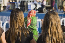 Back view of two girls with long  uncovered hair and elderly woman seen between them wearing headscarf. societyTurkishAegeancoastresortSummersunshineearly Summer seasonholidaydestinationdes...