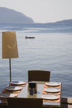Marmaris on the Turkish Riviera in early Summer season.  Woman sunbathing on lilo in flat calm water viewed from terrace of restaurant with prepared table laid for meal in foreground.Aegeancoastcoa...