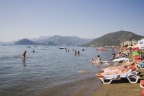 Marmaris on the Turkish Riviera in early summer season.   Foreign and Turkish tourists on busy beach in late afternoon sun with distant coastline beyond.resortholidayholidaymakersDestinationCrowd...