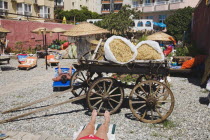 Marmaris on the Turkish Riviera in early summer season.  Tourists sunbathing in garden of resort hotel with display of traditional Turkish farm implements  tools and carts. coastcoastalresortholid...
