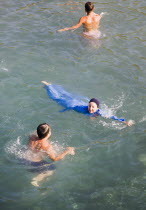 Olu Deniz.  Turkish woman wearing a Burkini  Muslim female swimwear and two other swimmers in clear water off Gemiler or St Nicholas island with Byzantine ruins under surface.Turkish rivieraAegeanc...