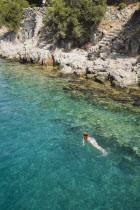 Female tourist swimming in clear  aquamarine water off Gemiler or St Nicholas Island with Byzantine ruins under water surface.Turkish RivieraAegeancoastcoastalresortholidayDestination Destinati...