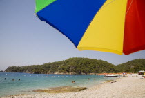 Olu Deniz.  Tourists swim at entrance to lagoon and beach rated in top five worldwide.  Part seen brightly coloured striped parasol in foreground.Turkish RivieraAegeancoastcoastalOludenizseasho...