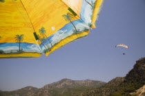 Olu Deniz.  Rated one of  the top five beaches worldwide and popular microlight and paragliding area.  Part seen yellow and blue parasol in foreground with Mount Babadag behind.Turkish RivieraAegean...