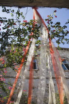Long red and white wedding ribbons hung over cobbled street in the Old Town with medieval walls part seen behind.AegeancoastcoastalWorld Heritage Siteformer Ottoman territorylocation for Guns of...