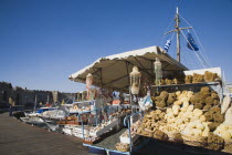 Rhodes Town  Mandraki Harbour.  Tourist souvenir stall on harbourside selling sponges from nearby Symi  and seashell crafts in late afternoon sunshine.AegeancoastcoastalFormer Ottoman territoryea...