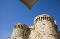 Rhodes Town.  Amboise Gate entrance to Old Town from beneath partly seen canopy of souvenir stall against bright blue  cloudless sky of early summer. AegeancoastcoastalFormer Ottoman territoryear...