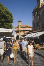 Rhodes Town.  Restored wooden tower of Ottoman era building on main shopping street of Odos Sokratous with tourists walking past open fronted cafes in late afternoon sunshine.AegeancoastcoastalFor...