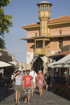 Rhodes Town.  Restored wooden tower of Ottoman era building on main shopping street of Odos Sokratous with tourists walking past open fronted cafes in late afternoon sunshine.AegeancoastcoastalFor...