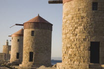 Old Town  Mandraki Harbour.  Medieval stone windmills on pier in clear late afternoon sun.Aegeancoast  coastalFormer Ottoman territoryearly Summer seasonlocation of Guns of Navaronepackage holid...