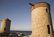 Old Town  Mandraki Harbour.  Medieval stone windmills on pier in clear late afternoon sun.Destination Destinations Ellada European Greek History Historic Rodos Southern Europe