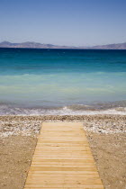 Ixia Beach outside Rhodes Town.  Wooden jetty used for water sports extending across beach towards clear  aquamarine water with Turkish coast beyond.GreekAegeanCoast - CoastalRodiPackage holiday...