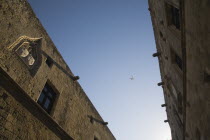 Holiday jet flies over Ippoton  or Street of the Knights.  The   oldest preserved medieval street in Europe in late afternoon sun.GreekAegeanCoast - CoastalRodiPackage holidaydestination destina...