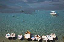 Lindos.  View over clear  shallow  aquamarine water of bay with line of moored boats in the foreground and tourists swiming in late afternoon sunshine.Greek IslandsAegeanRodicoast coastalseaswim...