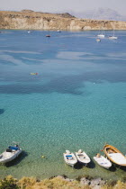 Lindos.  View over clear  shallow  aquamarine water of bay with boats moored in the foreground and tourists swiming in late afternoon sunshine.Greek IslandsAegeanRodicoast coastalsearesortholid...