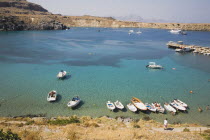 Lindos.  View over clear  shallow  aquamarine water of bay with boats moored in the foreground and tourists swiming in late afternoon sunshine.Greek IslandsAegeanRodicoast coastalsearesortholid...