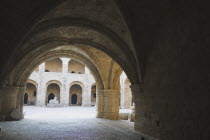 Stone archways framing view of courtyard and opposite colonnade.AegeanGreek IslandsRhodicoast coastalSummerresortholidaypackagetripDestination Destinations Ellada European Greek Southern Europe History Historic Rodos