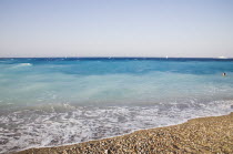 Rhodes Town.  Swimmer in clear  shallow  aquamarine water off Rhodes Town beach with white surf breaking on beach in the foreground.AegeanGreek IslandsRhodiSummerseacoast coastalresortholiday...