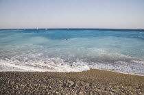Rhodes Town.  Swimmer in clear  shallow  aquamarine water off Rhodes Town beach with white surf breaking on beach in the foreground.AegeanGreek IslandsRhodiSummerseacoast coastalresortholiday...