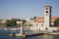 Rhodes Town.  Rhodes Port from boat deck with stag symbol of Rhodes on pillar and port authority building and clocktower behind. AegeanGreek IslandsRhodiharbour Summerseacoast coastalresortho...