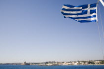 Approaching Rhodes Town from the sea with Greek flag flying in bright summer sun.AegeanGreek IslandsRhodiharbour Summerseacoast coastalresortholidaypackagetripDestination Destinations Ella...