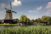 Windmill next to river or canal.HollandNetherlandsFlatWindmillWaterEuropeEuropean Benelux Dutch Nederland Western Europe