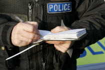 Policeman writing notes in his notepad.European LawOrderPolicePolicemanCopCopperBobbyWritin