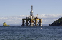 Scotland, Invergordon, Oil Rig Platform being pulled out to sea by tug vessel.ScotsWaterSeaOceanOilPetrolPetroeumRigPlatformDerrickDrillDrillingIndustryBoatShipBlue Ecology Entorno En...