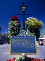 CANADA, Ontario, Niagara on the Lake, Queen Street. Plaque and hanging baskets.