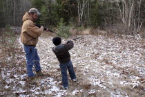 Tyler Stone and father Mike Stone  8 year old boy learning to shoot a shotgun.American North America Northern United States of America Dad Eight Immature Kids