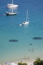 Pythagorio.  Yachts moored in bay with tourists swimming in clear  aquamarine water in early summer season.AegeanGreek IslandsPythagorionSummerseacoast coastalresortholidaypackagetripDestin...