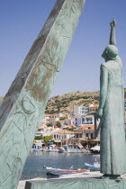 Pythagorio.  Statue of the philosopher and mathematician Pythagoras on waterfront with diagrams on plinth alongside framing view across harbour to houses on hillside beyond.AegeanGreek IslandsPitha...