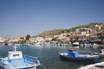 Pythagorio.  Small blue and white painted fishing boats  moored in Pythagorio bay with view towards waterfront buildings behind.AegeanGreek IslandsPithagorion Pythagorioncoast coastalseaSummerp...