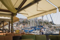 Pythagorio.  Cafe on waterfront with seating underneath stretched awning overlooking rental and sailing club yachts. AegeanGreek IslandsPithagorion Pythagorioncoast coastalseaSummerpackageholi...