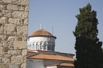 Pythagorio Metamorfosis Sotiros Greek orthodox Church.  Part view of white circular tower with blue painted detail and red tiled rooftops. North Eastern AegeanGreek IslandsPithagorion Pythagorionc...