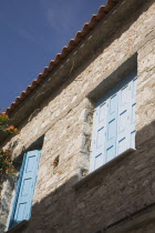 Pythagorio.  Detail of facade of traditional Greek farm cottage with blue painted window shutters and overhanging roof tiles.North Eastern AegeanGreek IslandsPithagorion Pythagorioncoast coastals...