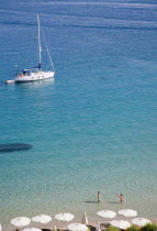 Pythagorio.  Tourists swimming in clear water in early Summer season with returning yacht in late afternoon  and line of parasols on beach part seen in the foreground.North Eastern AegeanGreek Islan...