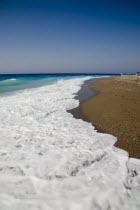 White surf breaking on quiet beach with clear blue sky above.  AegeanGreek IslandsSimicoast coastalseaSummerpackageholidayresortvacationtripdestinationDestinations ElladaEuropeanSouther...