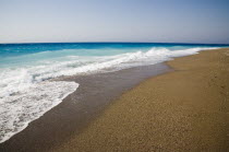 White surf breaking on empty  sandy beach with clear blue sky above.  AegeanGreek IslandsSimicoast coastalseaSummerpackageholidayresortvacationtripdestinationDestinations ElladaEuropean...