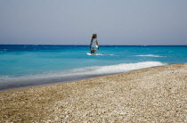 Empty stretch of beach with windsurfer on clear  aquamarine water beyond.AegeanGreek IslandsSimicoast coastalseaSummerpackageholidayresortvacationtripdestinationDestinations ElladaEurope...