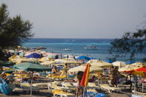 Yialos.  Stretch of beach crowded with sun umbrellas and loungers with pleasure boats on calm  aquamarine sea beyond.AegeanGreek IslandsSimicoast coastalseaSummerpackageholidayresortvacation...