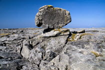 Limestone pavements  grykes  single narrow rock sits on a flat limestone section of the Burren.Eire European Irish Northern Europe Republic Ireland Poblacht na hEireann Blue Gray Karst Sedimentary Ro...