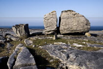 Large limestone boulder split in two with Atlantic Ocean in the background.Eire European Irish Northern Europe Republic Ireland Poblacht na hEireann 2 Blue Gray Karst Sedimentary Rock Scenic